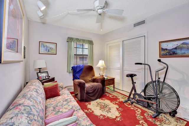 living room with a textured ceiling and ceiling fan