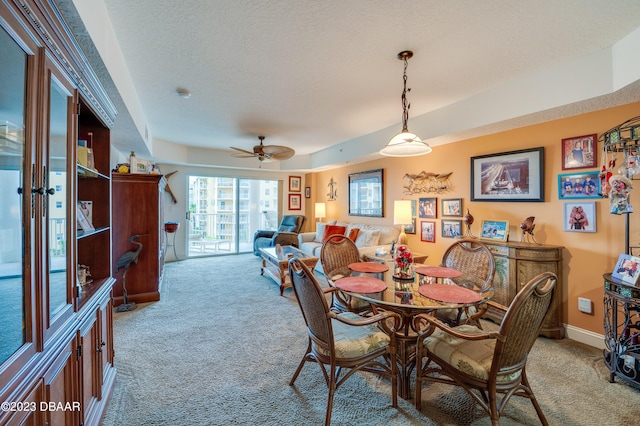 dining space with a tray ceiling, a textured ceiling, ceiling fan, and carpet floors