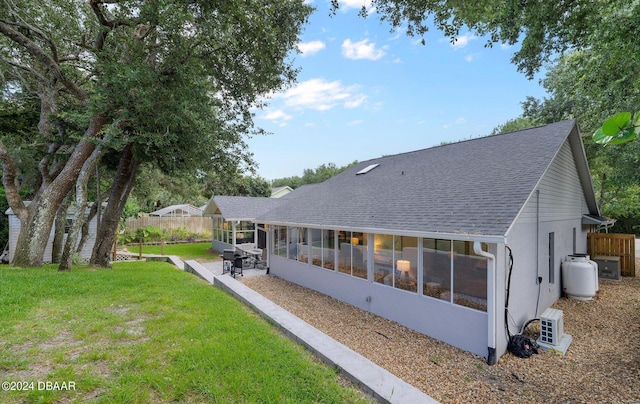 4791 S Peninsula Dr, Ponce Inlet, FL 32127 - back of property with a sunroom, a shingled roof, fence, and a yard