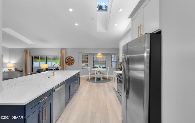4791 S Peninsula Dr, Ponce Inlet, FL 32127 - kitchen with a sink, light wood finished floors, stainless steel appliances, a skylight, and blue cabinets
