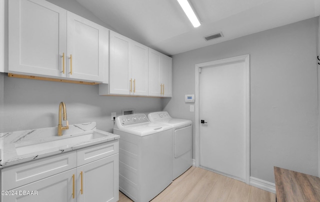 4791 S Peninsula Dr, Ponce Inlet, FL 32127 - washroom featuring independent washer and dryer, visible vents, cabinet space, a sink, and light wood-style flooring