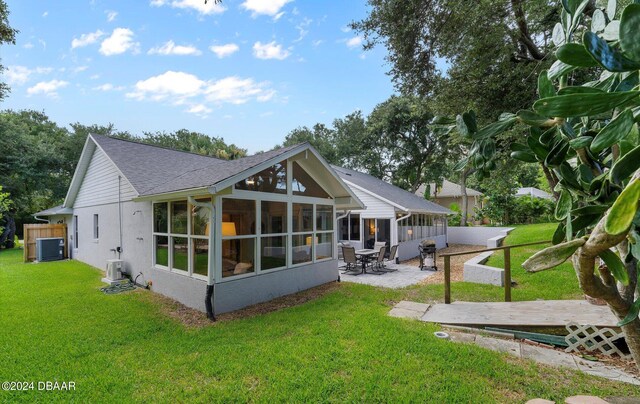 4791 S Peninsula Dr, Ponce Inlet, FL 32127 - rear view of house featuring stucco siding, a sunroom, cooling unit, a patio area, and a lawn