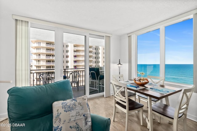 dining space featuring a water view, expansive windows, and a textured ceiling