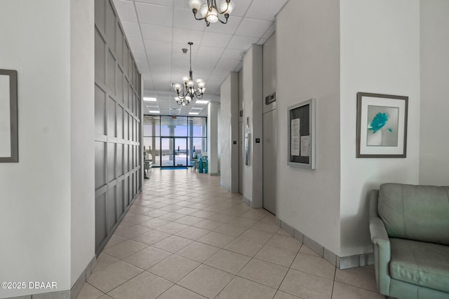 hall featuring expansive windows, light tile patterned flooring, a paneled ceiling, and an inviting chandelier