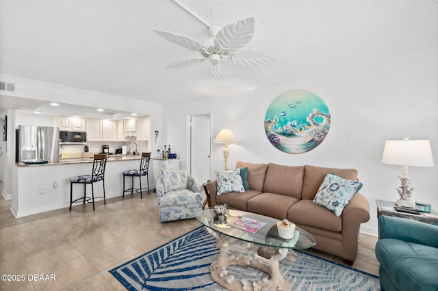 living room with light tile patterned flooring, sink, a textured ceiling, and ceiling fan