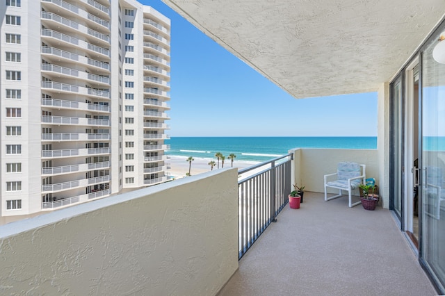 balcony with a water view and a view of the beach