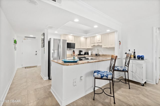 kitchen with sink, stainless steel fridge, light stone countertops, white cabinets, and kitchen peninsula