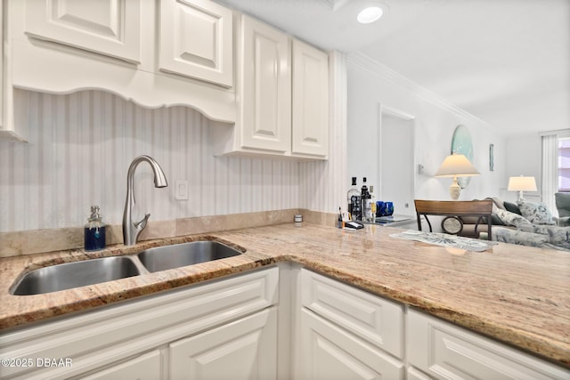 kitchen featuring sink, crown molding, light stone countertops, and white cabinets