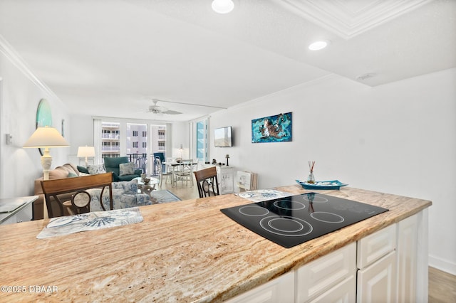 kitchen with white cabinetry, ornamental molding, black electric stovetop, and ceiling fan