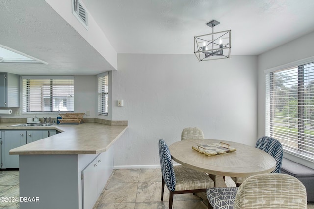 dining space with a chandelier, a textured ceiling, and sink