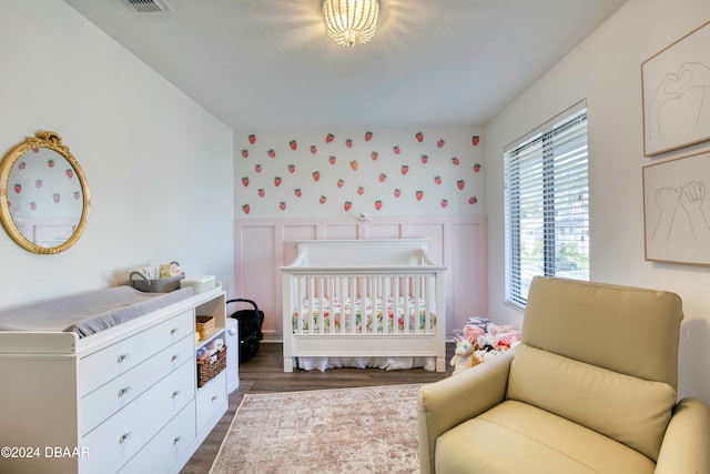 bedroom featuring dark wood-type flooring and a nursery area