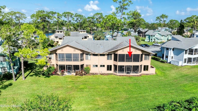 back of property with a sunroom and a lawn