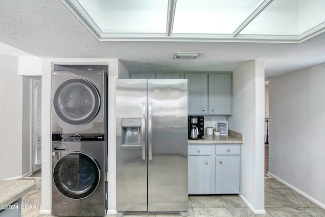 clothes washing area featuring stacked washing maching and dryer and a textured ceiling