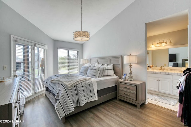 bedroom with access to exterior, vaulted ceiling, dark wood-type flooring, sink, and connected bathroom