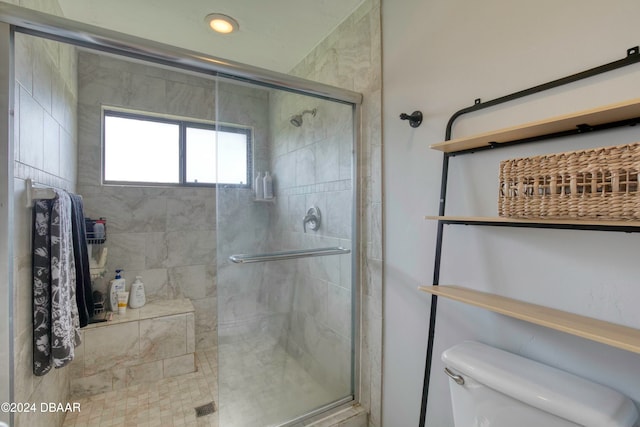 bathroom featuring toilet and a shower with shower door