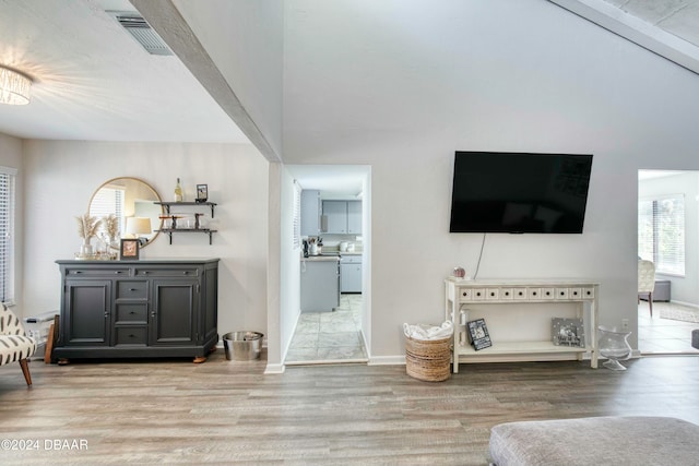 living room with vaulted ceiling with beams and light hardwood / wood-style flooring