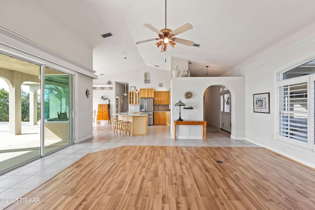 unfurnished living room featuring high vaulted ceiling, light hardwood / wood-style floors, and ceiling fan