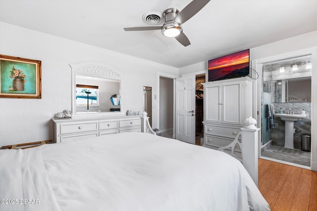 153 University Cir, Ormond Beach, FL 32176 - bedroom featuring wood finished floors, ensuite bath, and a ceiling fan