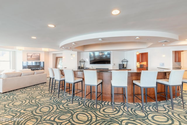 kitchen with a tray ceiling, a breakfast bar area, and carpet flooring