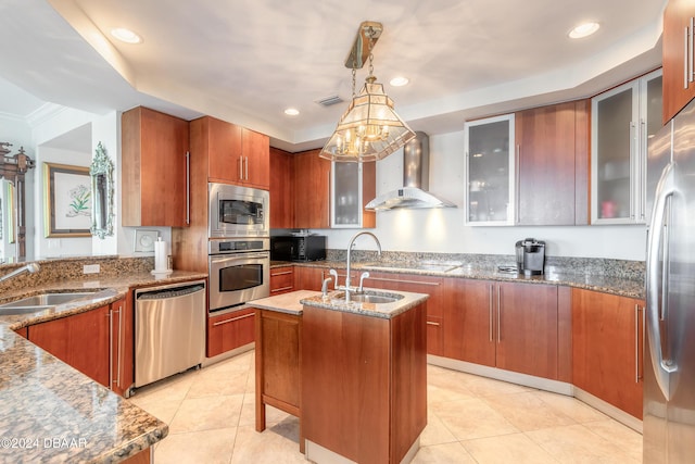 kitchen with a center island with sink, black appliances, sink, wall chimney range hood, and decorative light fixtures