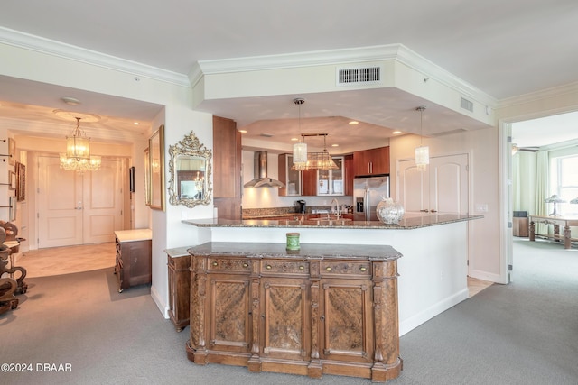 kitchen featuring light colored carpet, ornamental molding, pendant lighting, stainless steel refrigerator with ice dispenser, and wall chimney range hood