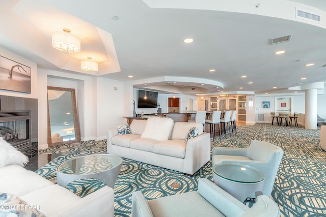 living room with tile patterned flooring, a fireplace, and a tray ceiling