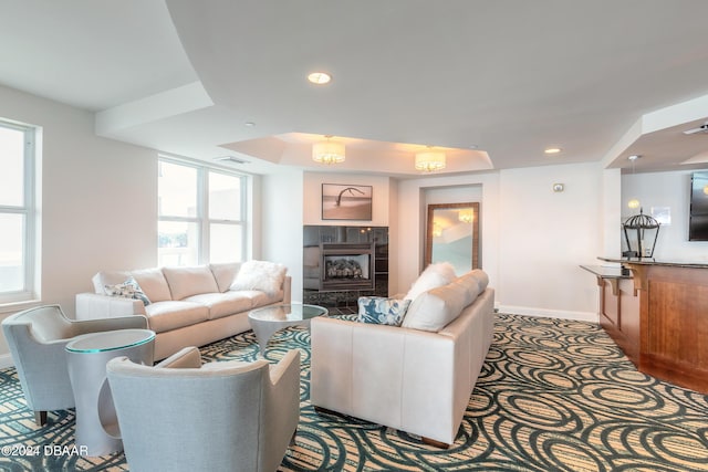 living room with a tiled fireplace and a tray ceiling