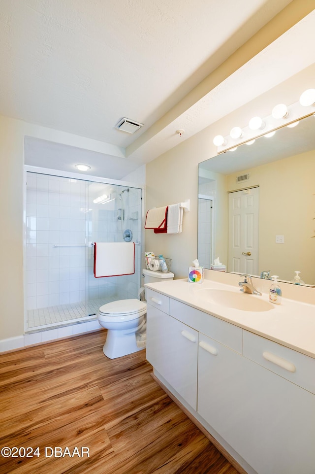 bathroom with hardwood / wood-style floors, vanity, toilet, and a shower with shower door