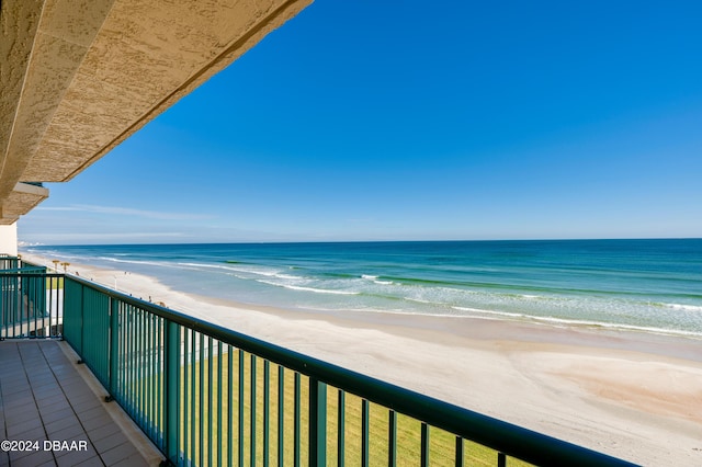 balcony with a water view and a view of the beach