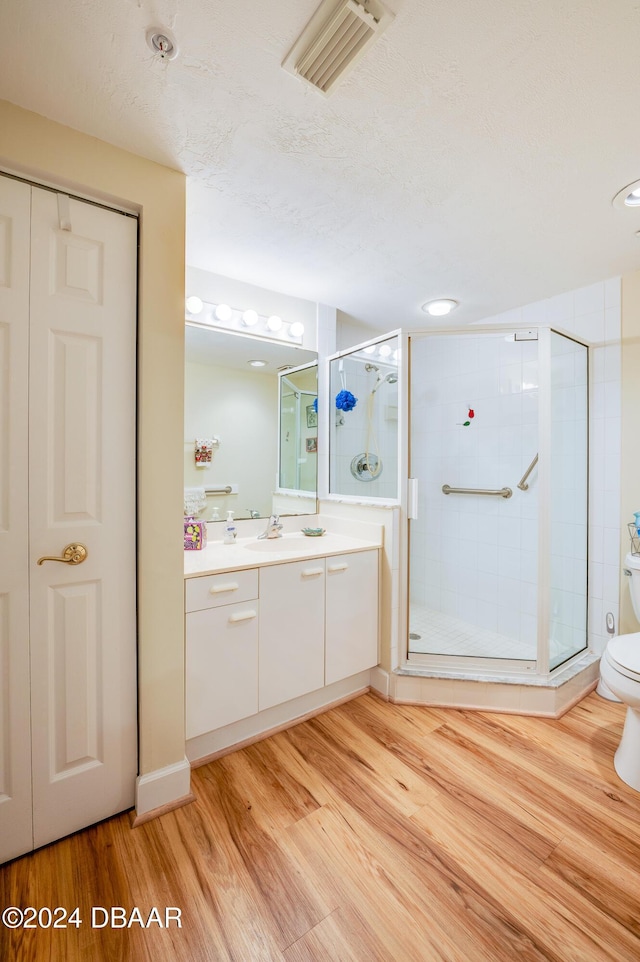 bathroom with vanity, hardwood / wood-style flooring, toilet, a textured ceiling, and an enclosed shower