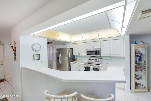 4555 S Atlantic Ave Unit 4310, Ponce Inlet, FL 32127 - kitchen with appliances with stainless steel finishes, light tile patterned floors, light countertops, a kitchen breakfast bar, and white cabinets