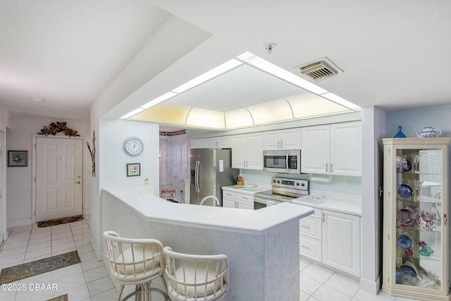 4555 S Atlantic Ave Unit 4310, Ponce Inlet, FL 32127 - kitchen featuring appliances with stainless steel finishes, light tile patterned floors, white cabinetry, light countertops, and a peninsula
