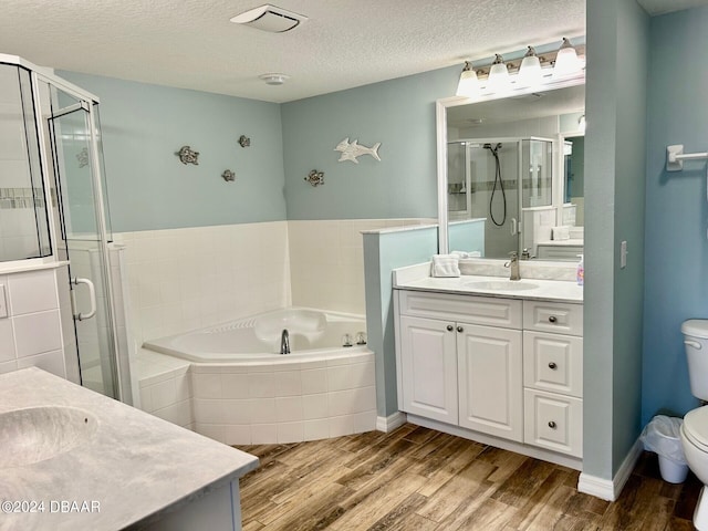 full bathroom featuring separate shower and tub, vanity, a textured ceiling, hardwood / wood-style flooring, and toilet