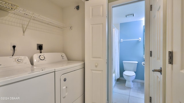 clothes washing area featuring light tile patterned floors and washing machine and clothes dryer