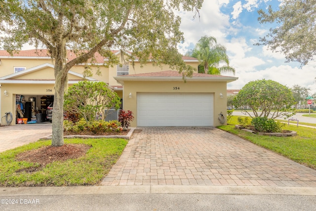 view of front of property featuring a garage, a front lawn, and central AC