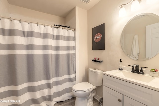 bathroom with toilet, vanity, and wood-type flooring