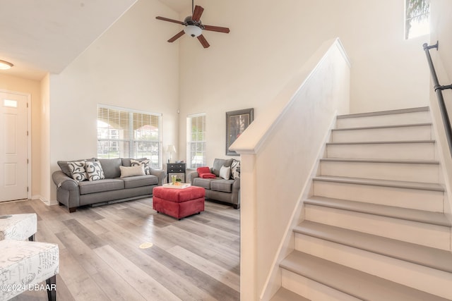 living room featuring light hardwood / wood-style floors, ceiling fan, and a high ceiling