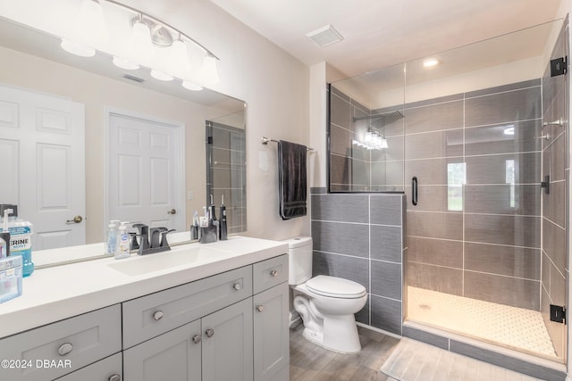 bathroom with wood-type flooring, vanity, a shower with door, and toilet