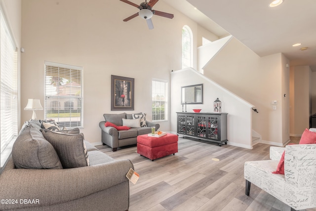 living room featuring a high ceiling, plenty of natural light, and light hardwood / wood-style flooring