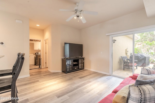 living room with light hardwood / wood-style floors, washer / clothes dryer, and ceiling fan