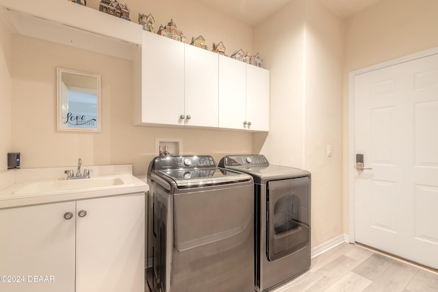 laundry area featuring light hardwood / wood-style floors, cabinets, sink, and washer and clothes dryer