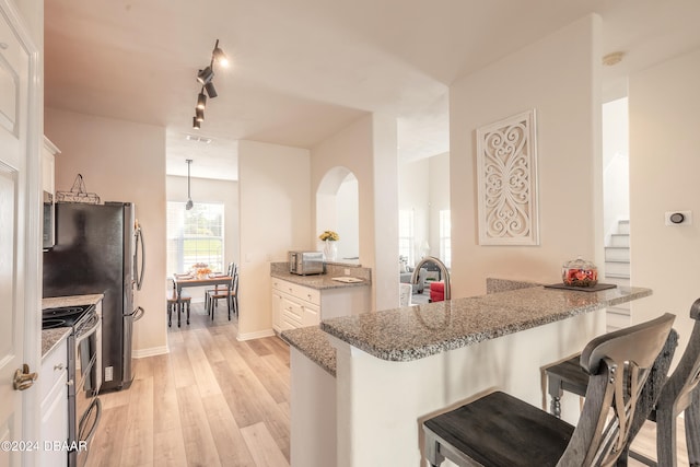 kitchen featuring white cabinets, kitchen peninsula, stainless steel range with electric stovetop, and light hardwood / wood-style flooring