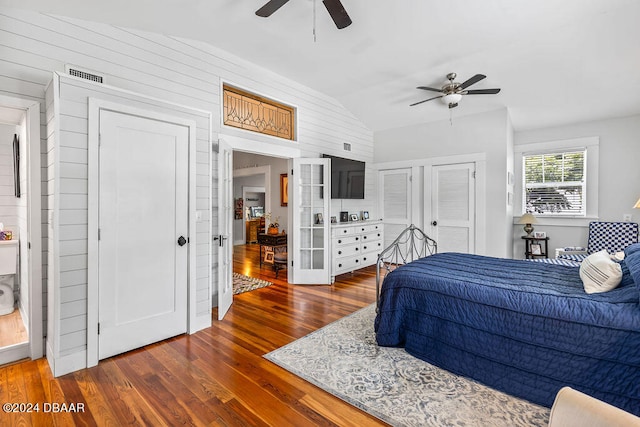 509 Faulkner St, New Smyrna Beach, FL 32168 - bedroom featuring multiple closets, wooden walls, vaulted ceiling, dark wood-type flooring, and ceiling fan
