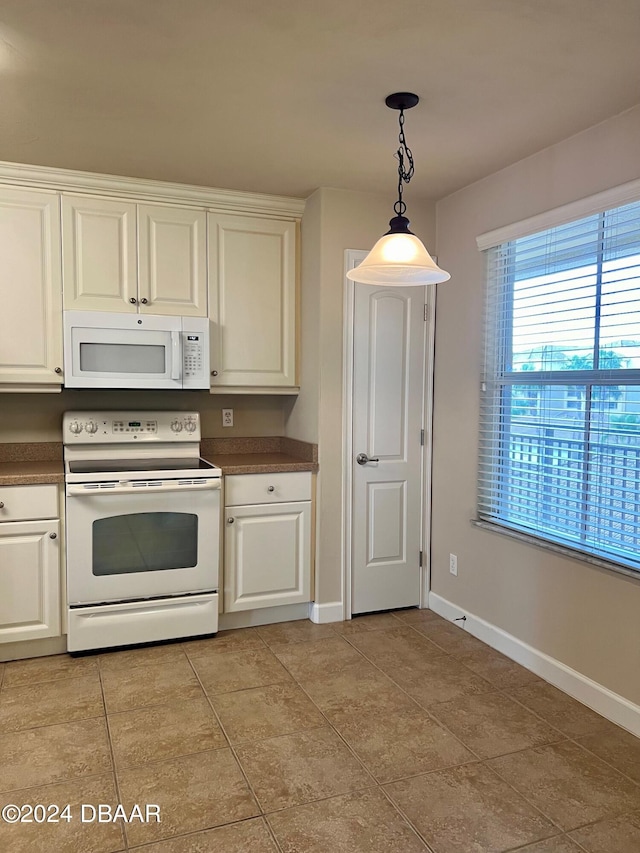 kitchen with decorative light fixtures, light tile patterned floors, and white appliances