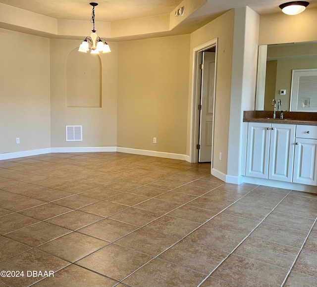 empty room featuring a chandelier and sink