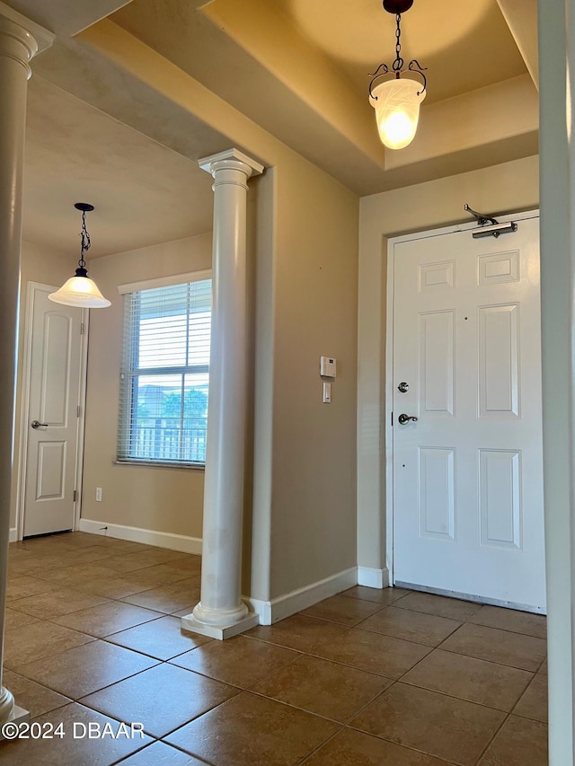 tiled entryway featuring a raised ceiling and ornate columns