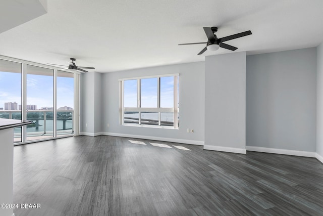 unfurnished room featuring a water view, dark hardwood / wood-style floors, and ceiling fan