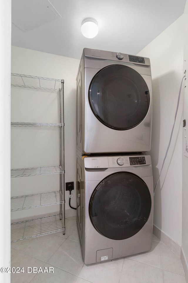 laundry room with light tile patterned floors and stacked washer / dryer