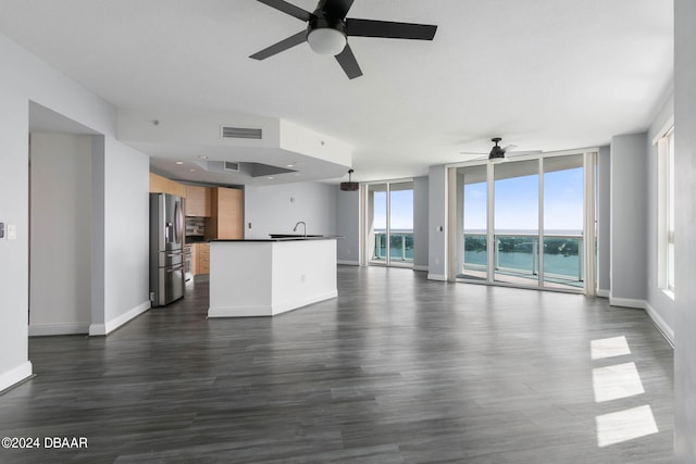 unfurnished living room with plenty of natural light, a water view, dark hardwood / wood-style floors, and sink