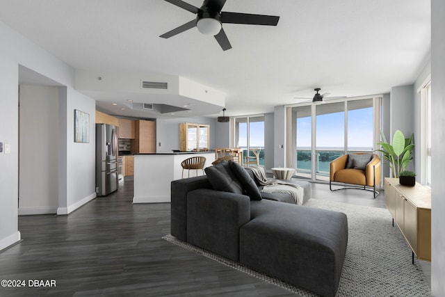 living room featuring a water view, dark wood-type flooring, and ceiling fan